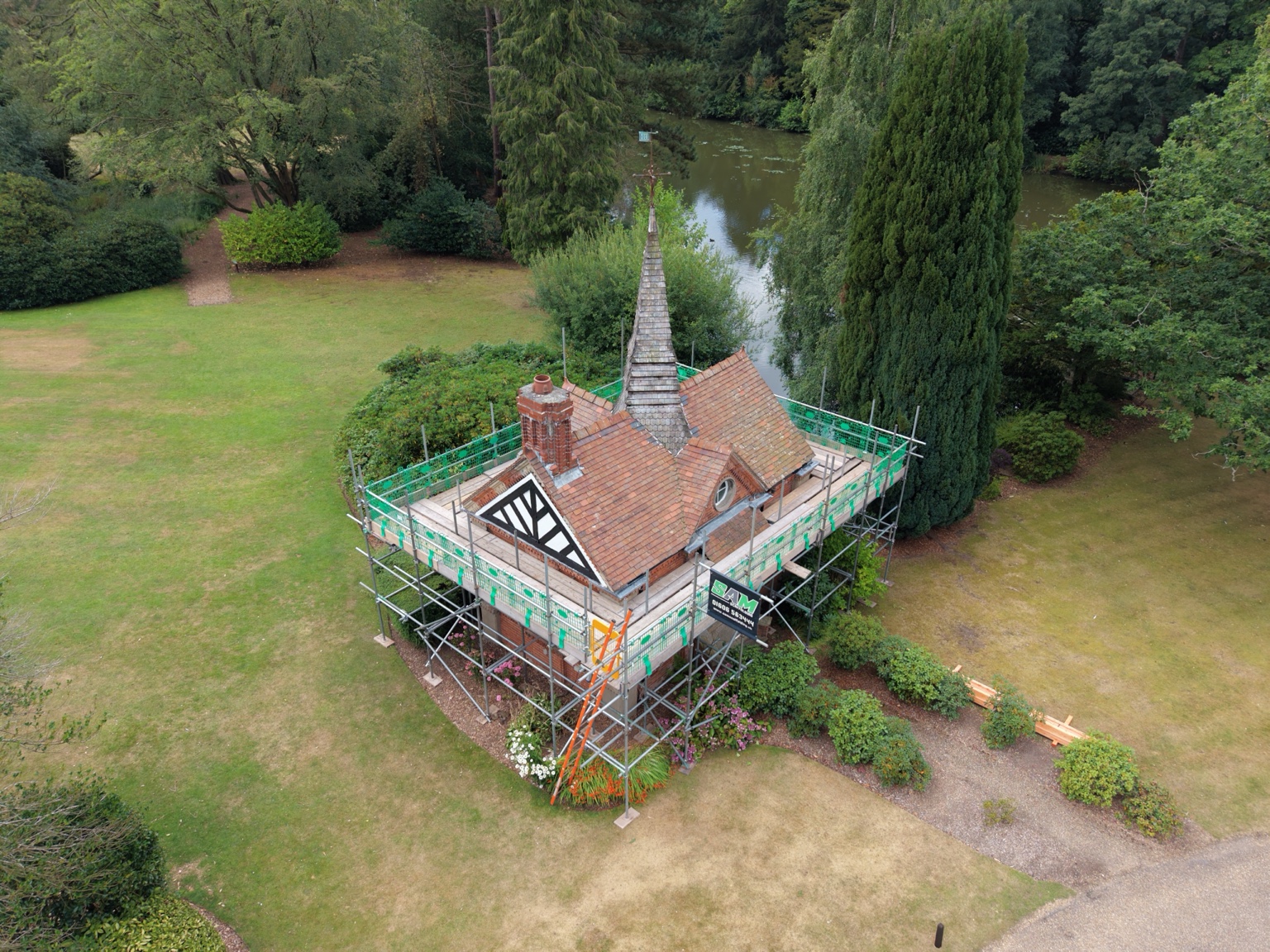 Scaffolding around the Victorian boathouse at Bostock Hall, with the lake and gardens behind